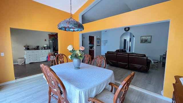 dining space with hardwood / wood-style flooring and high vaulted ceiling