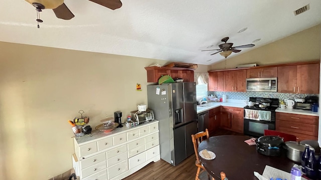 kitchen featuring tasteful backsplash, appliances with stainless steel finishes, vaulted ceiling, dark wood-type flooring, and ceiling fan