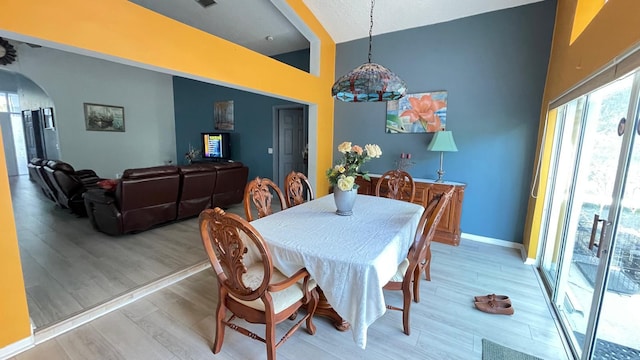 dining space featuring light wood-type flooring and high vaulted ceiling