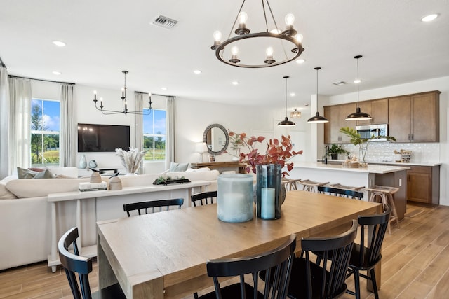 dining room with a wealth of natural light, an inviting chandelier, and light hardwood / wood-style floors