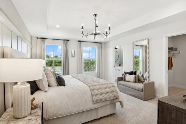 carpeted bedroom with a closet, an inviting chandelier, a spacious closet, and connected bathroom