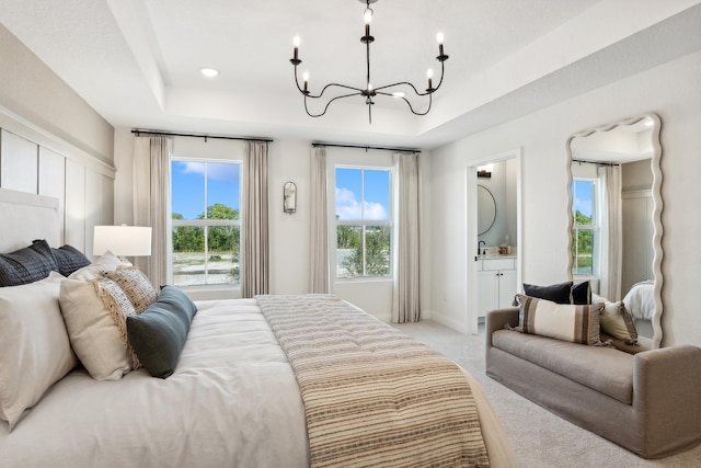 bedroom with connected bathroom, multiple windows, a tray ceiling, and light colored carpet