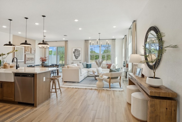 living room featuring a chandelier, sink, and light wood-type flooring