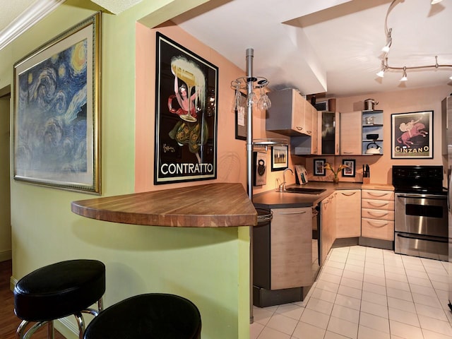 kitchen featuring sink, light tile patterned flooring, stainless steel range oven, kitchen peninsula, and light brown cabinets