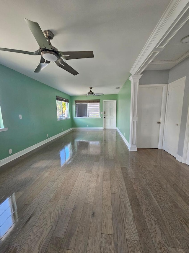 spare room with dark wood-type flooring, decorative columns, baseboards, and ceiling fan