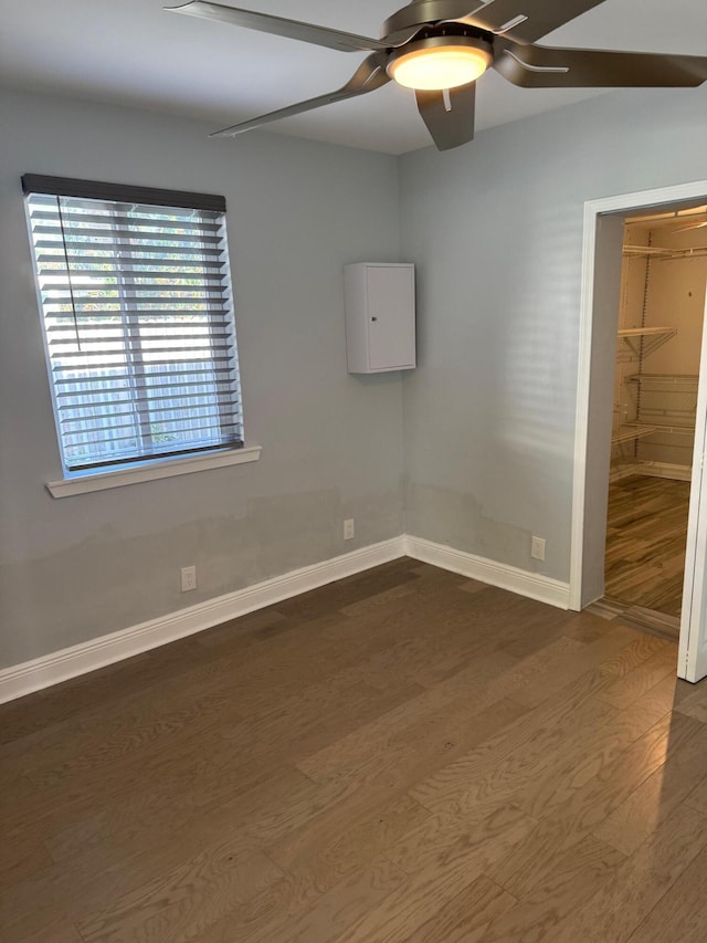 empty room featuring dark wood finished floors, baseboards, and ceiling fan