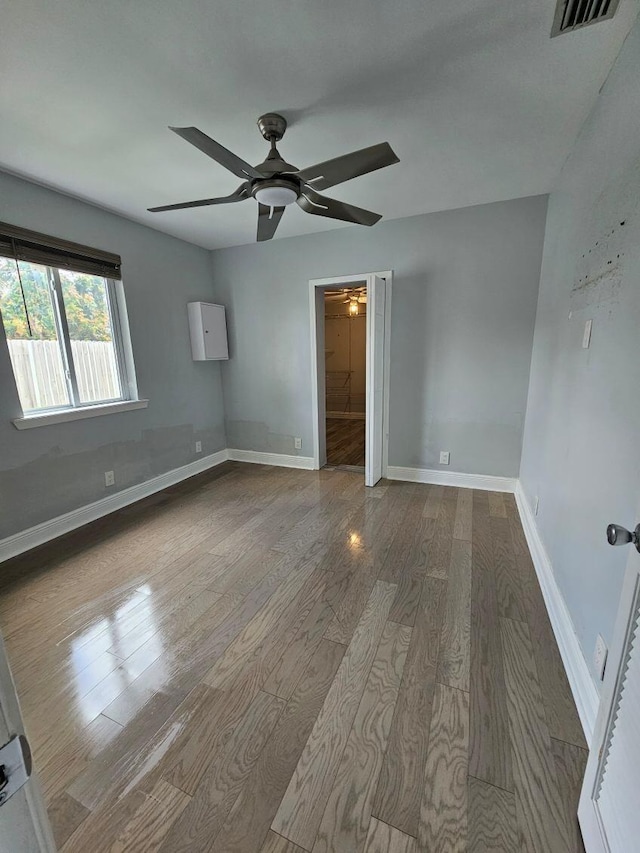 unfurnished bedroom featuring baseboards, visible vents, a ceiling fan, wood finished floors, and ensuite bathroom