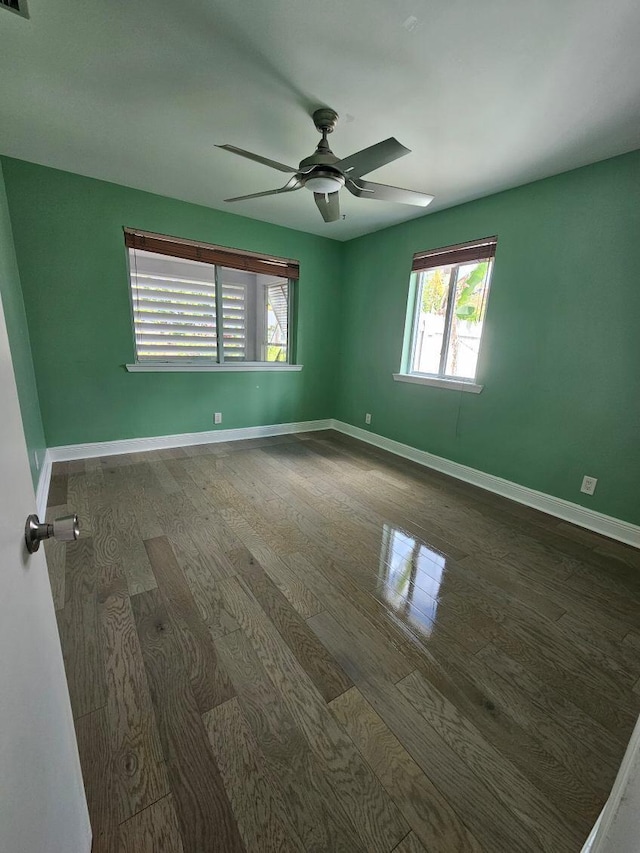 unfurnished room featuring a ceiling fan, dark wood finished floors, and baseboards