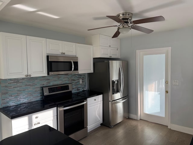 kitchen with stainless steel appliances, dark countertops, white cabinets, and decorative backsplash