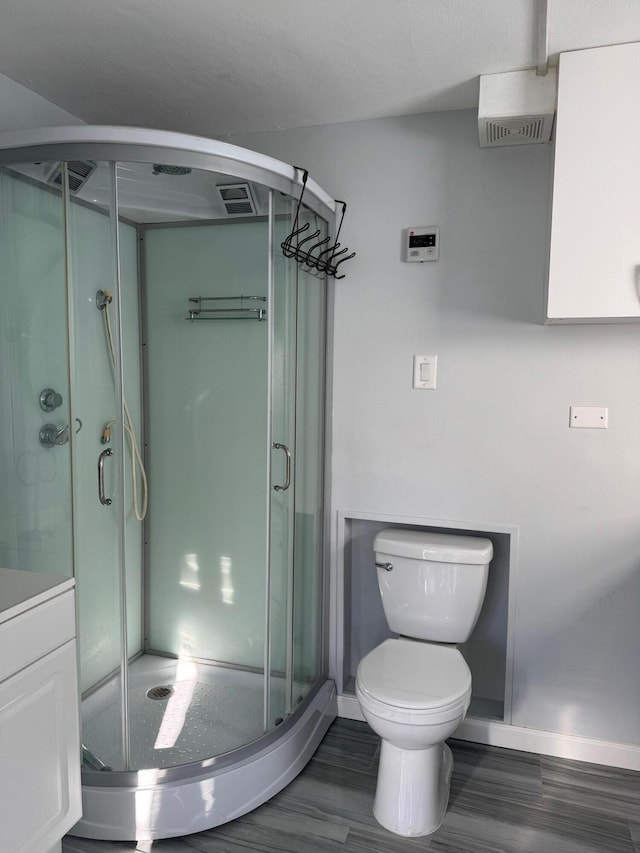 full bath featuring a stall shower, baseboards, vanity, and toilet