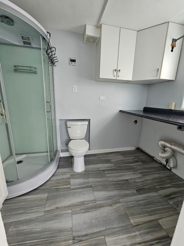 bathroom featuring a stall shower, baseboards, visible vents, and toilet