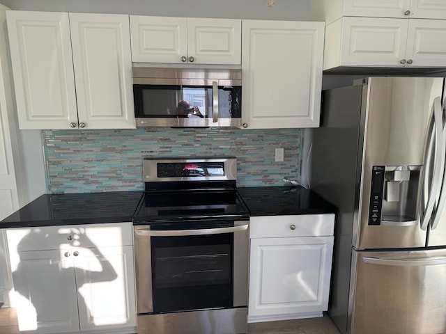 kitchen with appliances with stainless steel finishes, dark countertops, and white cabinetry