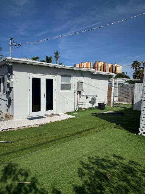 back of house featuring french doors, stucco siding, a yard, and fence