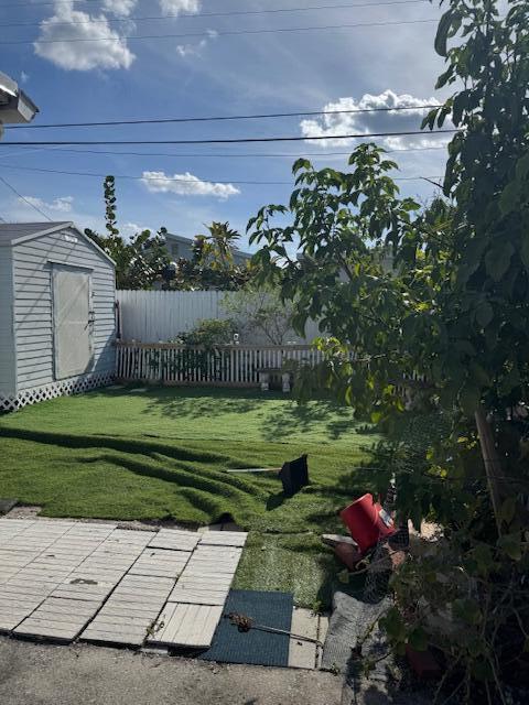 view of yard featuring fence, an outdoor structure, and a storage unit