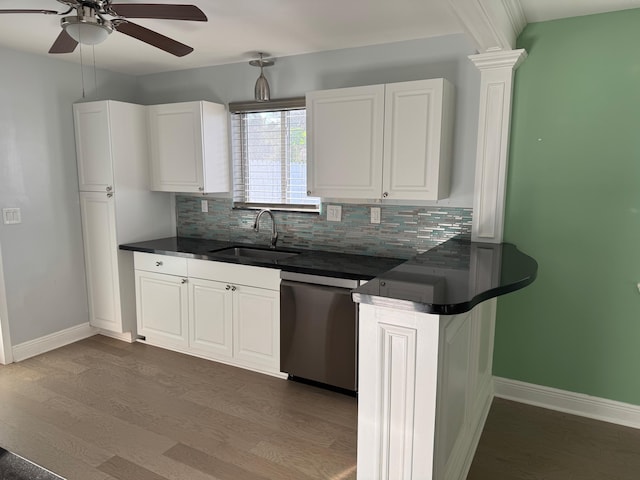 kitchen with dark countertops, dark wood-type flooring, a sink, white cabinetry, and stainless steel dishwasher