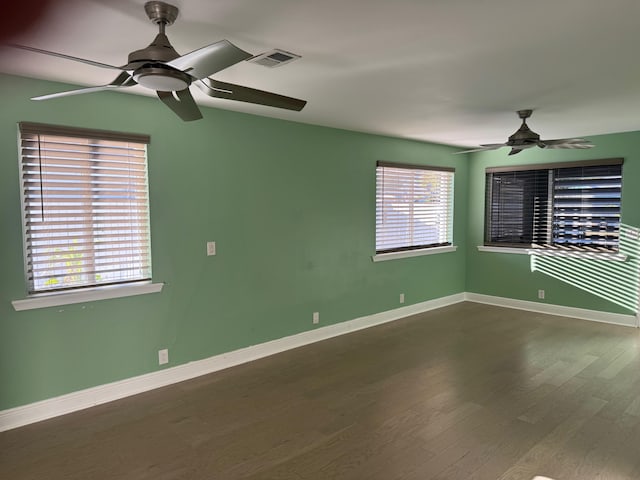 spare room featuring baseboards, wood finished floors, visible vents, and a healthy amount of sunlight