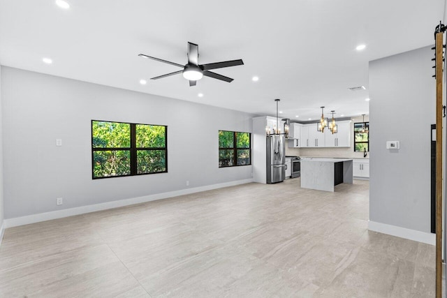 unfurnished living room featuring plenty of natural light and ceiling fan with notable chandelier