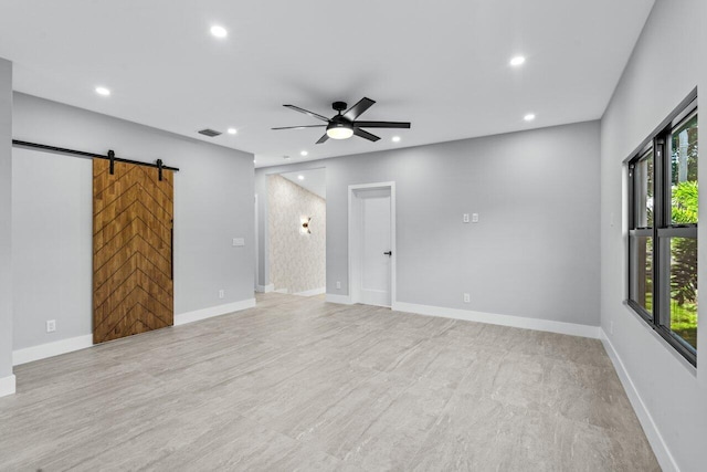 spare room with a barn door and ceiling fan