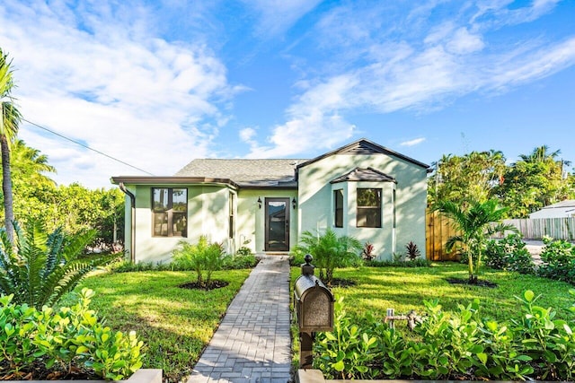 view of front of property featuring a front yard, fence, and stucco siding