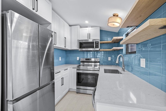 kitchen featuring tasteful backsplash, appliances with stainless steel finishes, white cabinetry, sink, and light stone counters