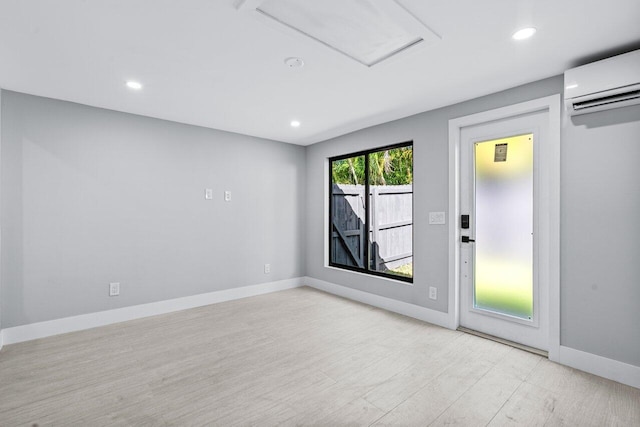 spare room featuring a wall unit AC and light wood-type flooring