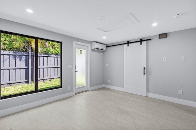 empty room featuring a wealth of natural light, a wall mounted AC, and a barn door