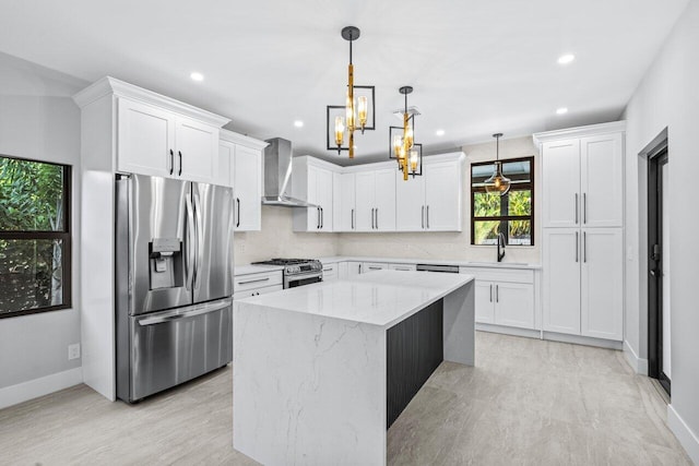 kitchen featuring wall chimney exhaust hood, appliances with stainless steel finishes, a center island, and white cabinets