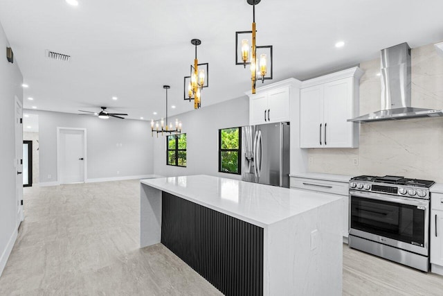 kitchen with wall chimney exhaust hood, white cabinetry, stainless steel appliances, and pendant lighting