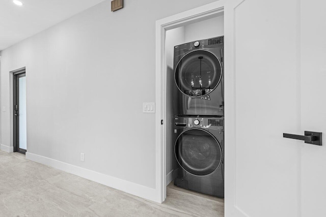 clothes washing area with stacked washer and dryer and light colored carpet