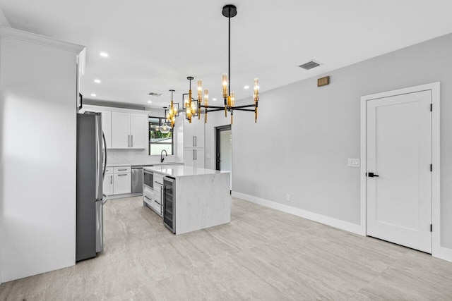 kitchen featuring appliances with stainless steel finishes, a center island, pendant lighting, white cabinets, and wine cooler