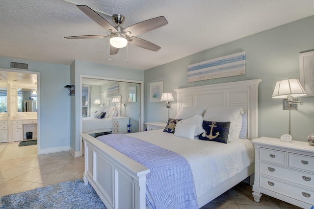 tiled bedroom featuring ceiling fan, connected bathroom, a textured ceiling, and a closet