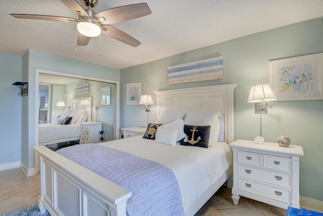 bedroom featuring light tile patterned flooring, ceiling fan, a closet, and a textured ceiling