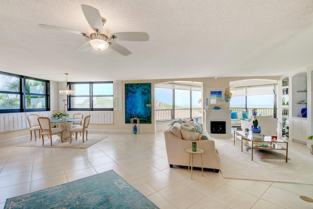 living room with ceiling fan, a textured ceiling, and light tile patterned floors