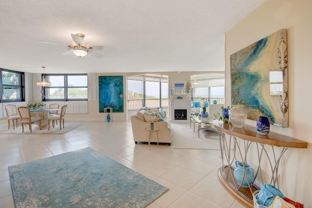 living room with light tile patterned floors, a textured ceiling, and ceiling fan