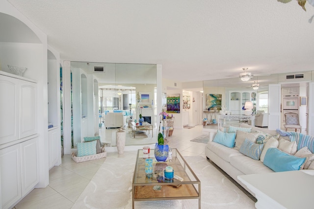 tiled living room featuring ceiling fan and a textured ceiling