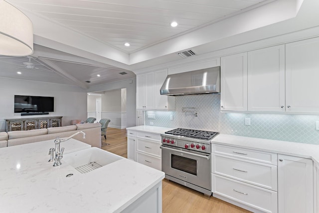 kitchen featuring light hardwood / wood-style flooring, premium stove, white cabinetry, and wall chimney exhaust hood