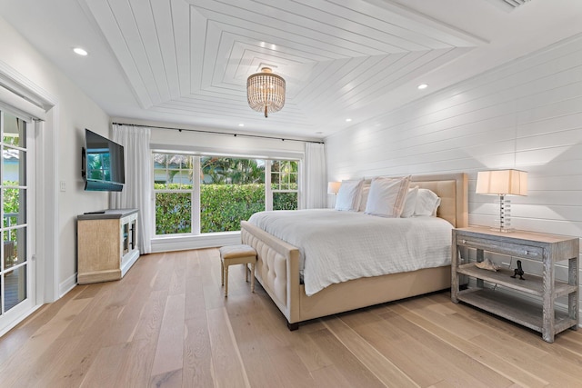 bedroom featuring an inviting chandelier, light hardwood / wood-style flooring, and multiple windows