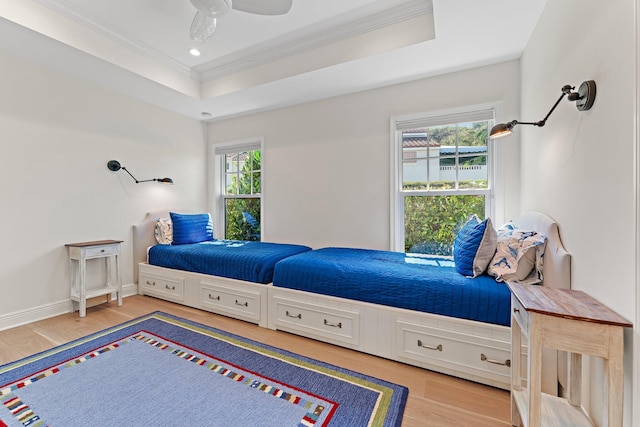 bedroom with a raised ceiling, ceiling fan, hardwood / wood-style floors, and crown molding