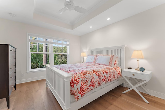 bedroom with a raised ceiling, ceiling fan, hardwood / wood-style floors, and ornamental molding