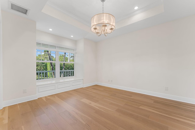 unfurnished room featuring a chandelier, hardwood / wood-style flooring, a raised ceiling, and crown molding