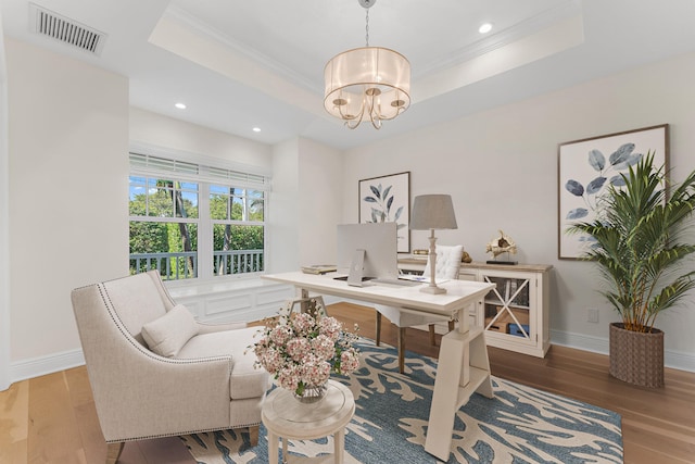 office area featuring a tray ceiling, ornamental molding, and light wood-type flooring