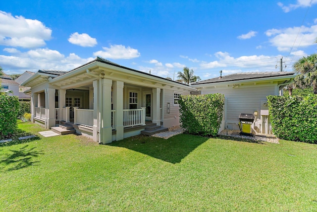 rear view of property with a lawn and covered porch