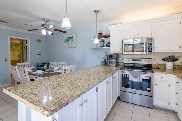 kitchen with appliances with stainless steel finishes, kitchen peninsula, pendant lighting, white cabinets, and decorative backsplash