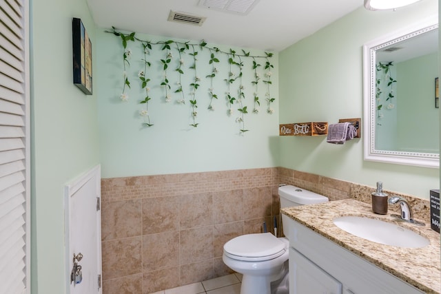 bathroom featuring tile walls, vanity, toilet, and tile patterned floors