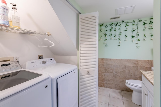 laundry room featuring tile walls, separate washer and dryer, and light tile patterned floors