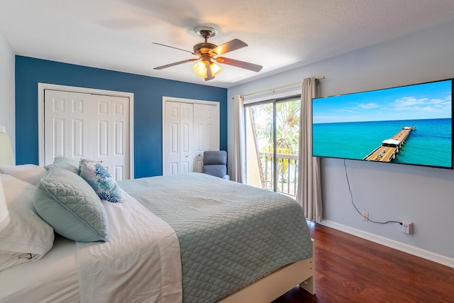 bedroom with two closets, dark hardwood / wood-style flooring, ceiling fan, a textured ceiling, and access to exterior