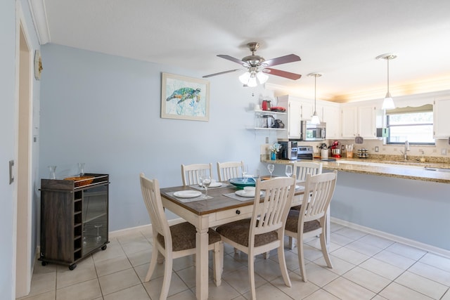 tiled dining area featuring ceiling fan and sink