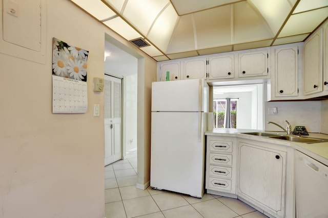 kitchen with white cabinets, sink, light tile patterned floors, and white appliances