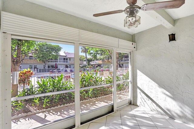 doorway to outside with ceiling fan, beamed ceiling, light tile patterned floors, and plenty of natural light