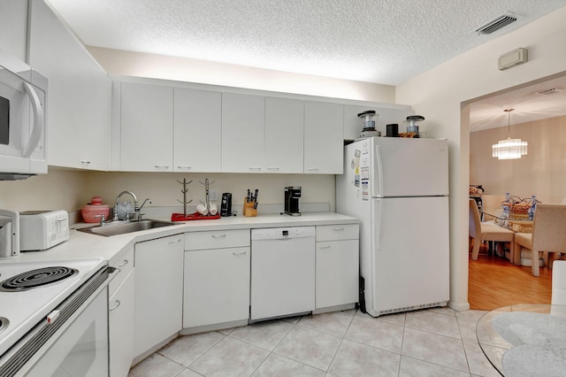 kitchen with sink, an inviting chandelier, light tile patterned flooring, white appliances, and white cabinets